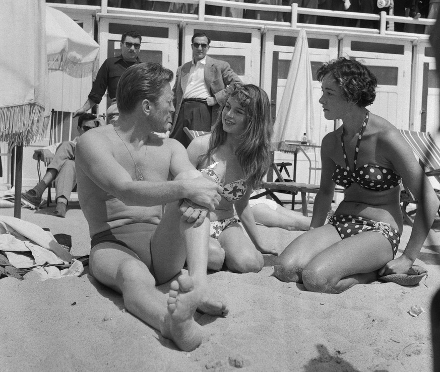 (Original Caption) American actor Kirk Douglas seems engrossed in conversation with pretty French starlet Brigitte Bardot, as they sun themselves on the Cote D&#039; Azur sand, 1953