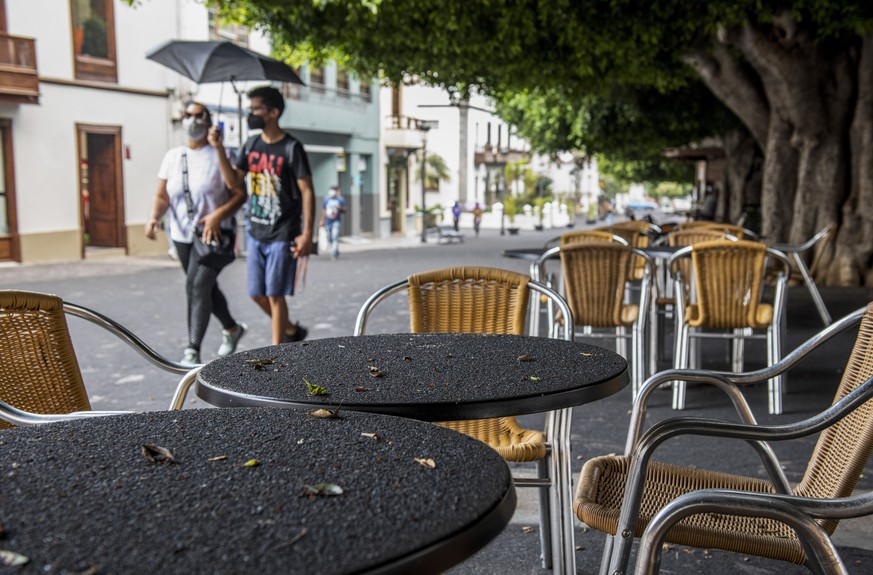 People walk on a street covered with ash from a volcano on the Canary Island of La Palma, in Los Llanos de Aridane, Spain on Friday Oct. 1, 2021. An erupting volcano on a Spanish island off northwest  ...