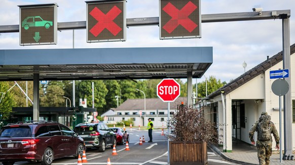 23.08.2024, Nordrhein-Westfalen, Geilenkirchen: Am Morgen kontrollieren Soldaten die Einfahrt in die Nato Air Base, ein Soldat in Tarnkleidung ist zu Fu