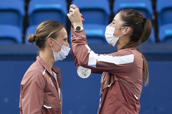 epa09384490 Switzerland's Belinda Bencic (R) hands over the silver medal to her teammate Viktorija Golubic after the women's tennis doubles gold medal match against Barbora Krejcikova and Ka ...