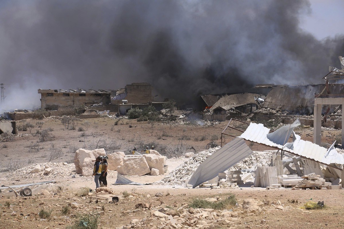 In this photo provided by the Syrian Civil Defense White Helmets, Syrian Civil Defense workers inspect the explosion side in Maarat Misrin village, in Idlib province, north Syria, Thursday, July, 24,  ...