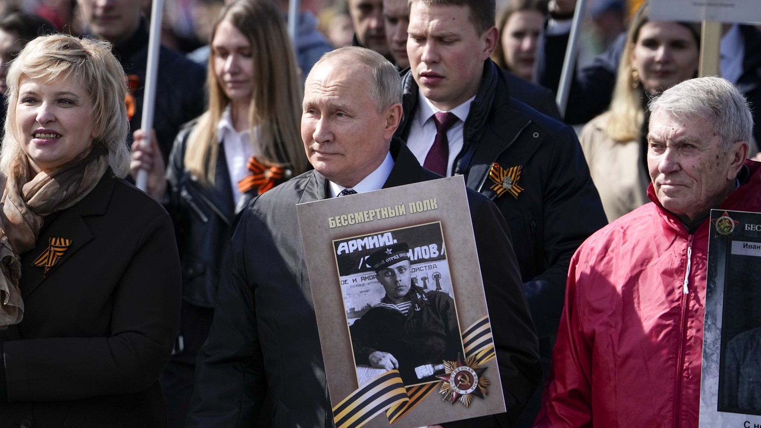 Russian President Vladimir Putin, center, attends the Immortal Regiment march through Red Square marking the 77th anniversary of the end of World War II, in Moscow, Russia, Monday, May 9, 2022. (AP Ph ...