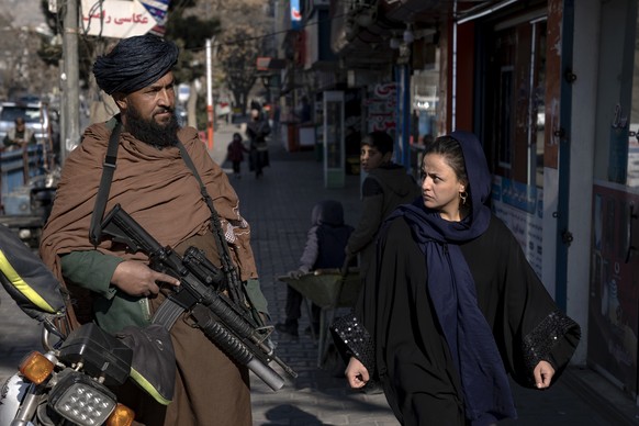 A Taliban fighter stands guard as a woman walks by in Kabul, Afghanistan, Monday, Dec. 11.  26, 2022. Recent Taliban rulings on Afghan women include a ban on university education and working for NGOs, spa...