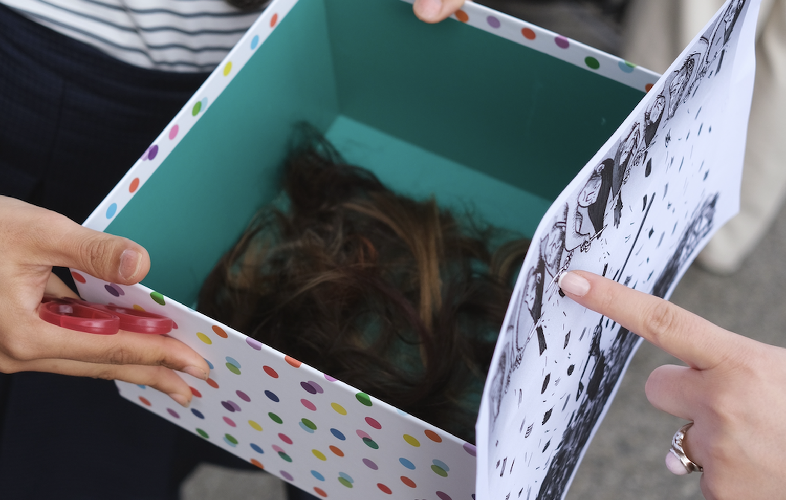 Eine Frau sammelt in einer Box abgeschnittene Haare ein.