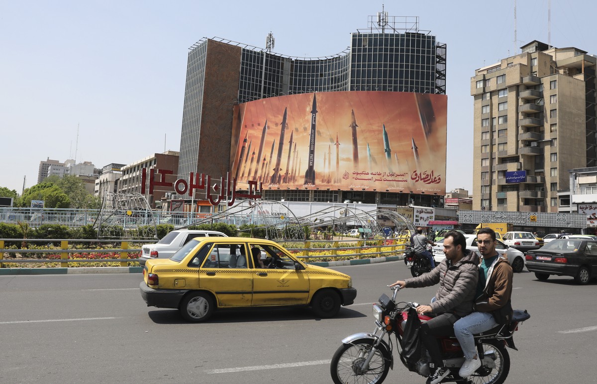 Des Iraniens passent devant un panneau d'affichage anti-israélien montrant des photos de missiles iraniens à Téhéran, Iran, 15 avril 2024.