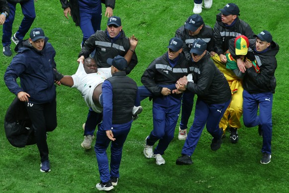 Senegal supporters are taken from the stadium by security officers after a controversial penalty was awarded to Morocco late on during the Africa Cup of Nations final soccer match between Senegal and  ...