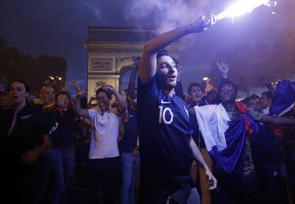 People celebrate on the Champs Elysees avenue, with the Arc de Triomphe in background, after the semifinal match between France and Belgium at the 2018 soccer World Cup, Tuesday, July 10, 2018 in Pari ...