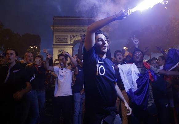 People celebrate on the Champs Elysees avenue, with the Arc de Triomphe in background, after the semifinal match between France and Belgium at the 2018 soccer World Cup, Tuesday, July 10, 2018 in Pari ...