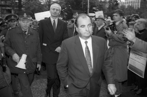 Unter gellenden Pfiffen wird Fuerst Hans-Adam II. von Liechtenstein, Mitte, am 29. Oktober 1992 in Vaduz von Polizisten und Regierungschef Hans Brunhart, vorne, durch die aufgebrachte Menge geleitet.  ...