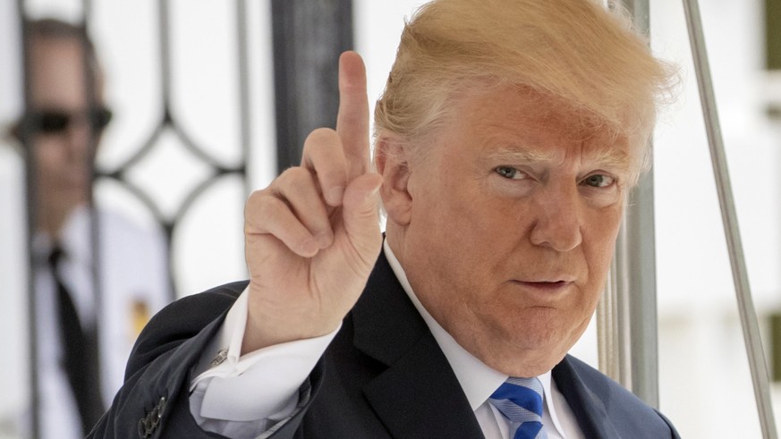 In this May 4, 2018 photo, President Donald Trump signals to the press that he will come over to talk, as he leaves the White House for Dallas to address the National Rifle Association in Washington.  ...