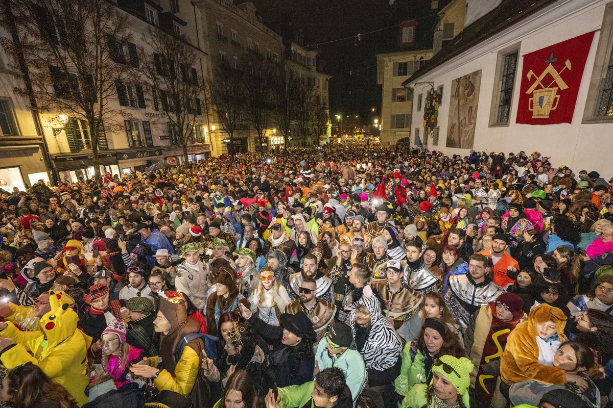 Fasnaechtler warten den 'Foetzeliraege' auf dem Kapellplatz an der Fritschi-Tagwache der Luzerner Fasnacht am Schmutzigen Donnerstag, 8. Februar 2024 in Luzern. Die Luzerner Fasnacht dauert  ...