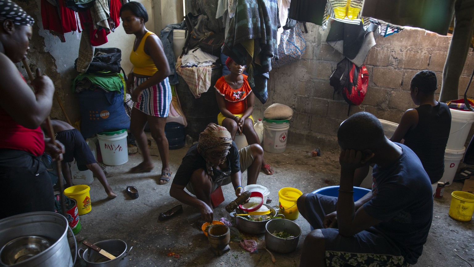 A woman prepares food at a shelter for families displaced by gang violence in Port-au-Prince, Haiti, Thursday, Dec. 9, 2021. A spike in violence has deepened hunger and poverty in Haiti while hinderin ...
