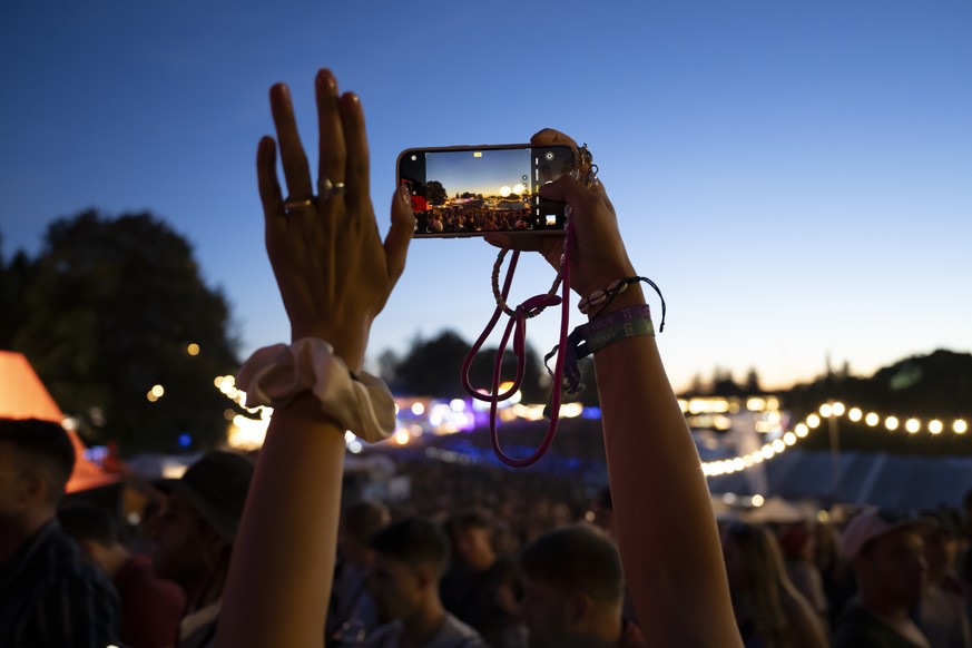 A festival goer takes a picture with his smartphone at the 40th Gurtenfestival edition, in Bern, Switzerland, on Friday, July 14, 2023. The open air music festival runs from 12 to 16 July. (KEYSTONE/A ...
