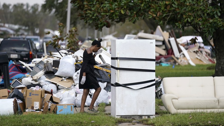 FILE - Lori Butler wipes her brow as she moves debris she is gutting from her home that was flooded, in the aftermath of Hurricane Ida in LaPlace, La., Tuesday, Sept. 7, 2021. At least a half dozen go ...