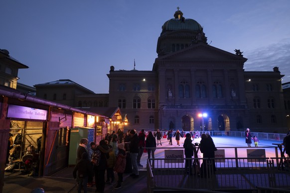 People enjoy ice skating on a temporary ice track named Kunsteisbahn Bundesplatz in front of the federal parliament building on the federal square, in Bern, Switzerland, Sunday, December 18, 2022. (KE ...