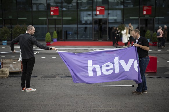 Mitarbeiter rollen Fahnen der Helvetia ein, nach der ausserordentlichen Generalversammlung der Helvetia Versicherungen, am Freitag, 23. Mai 2025, in St. Gallen. Die beiden fuehrenden Schweizer Versich ...