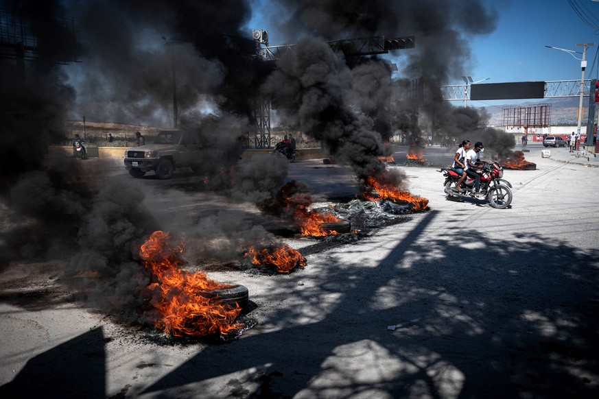 epaselect epa10432159 People navigate through burning street barricades during protests, in Port-au-Prince, Haiti, 26 January 2023. A protest spurred by police officers that reached the private reside ...