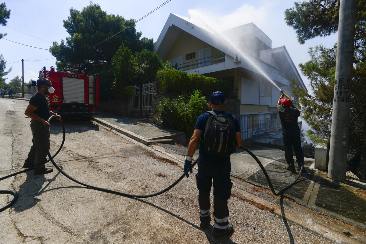 A firefighter tries to extinguish a burning embers on a house, in Thrakomacedones area, in northern Athens, Greece, Saturday, Aug. 7, 2021. Wildfires rampaged through massive swathes of Greece's  ...