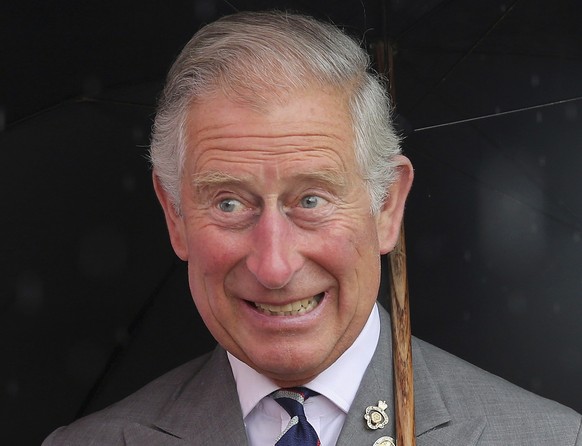 Britain's Prince Charles receives a teddy bear for Prince George of Cambridge while visiting the 132nd Sandringham Flower Show at Sandringham House, England, Wednesday, July 31, 2013. The Pri...