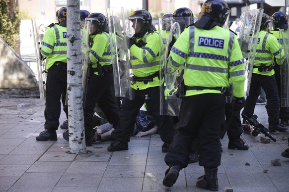 Police shield an injured man during a protest in Liverpool, England, Saturday Aug. 3, 2024, following the stabbing attacks on Monday in Southport, in which three young children were killed. (James Spe ...