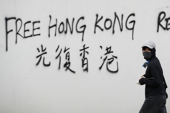 A protester spray-paints a slogan on a wall during a demonstration in Hong Kong, Saturday, Aug. 3, 2019. Hong Kong protesters ignored police warnings and streamed past the designated endpoint for a ra ...