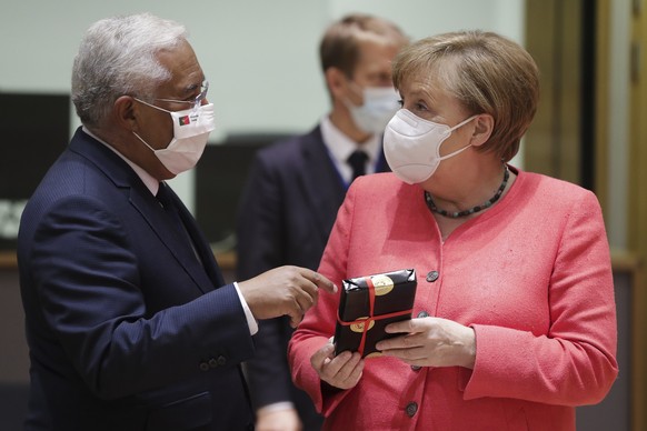 epa08551243 Portuguese Prime Minister Antonio Costa (L) gives a present to Germany&#039;s Chancellor Angela Merkel (R) at the start of an EU summit at the European Council building in Brussels, Belgiu ...