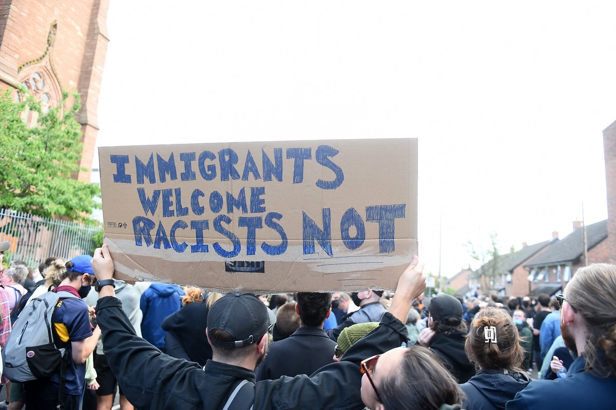 epa11534479 An anti-racist protester holds up a sign outside the Merseyside Refugee Centre in Liverpool, Britain, 07 August 2024. Further far-right protests are expected throughout Britain on the 07 A ...