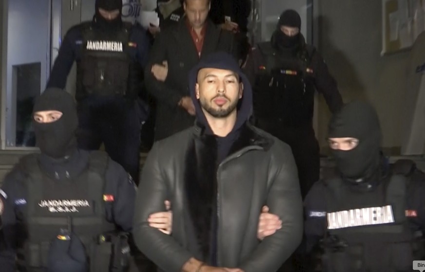 In this grab taken from video released by Observator Antena 1, Social Media personality Andrew Tate is led away by police, in the Ilfov area, north of Bucharest, Romania, Thursday, Dec. 29, 2022. Roma ...