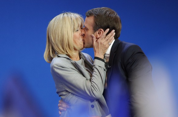 FILE - In this April 23, 2017 file photo, French centrist presidential candidate Emmanuel Macron kisses his wife Brigitte before addressing his supporters at his election day headquarters in Paris. Br ...