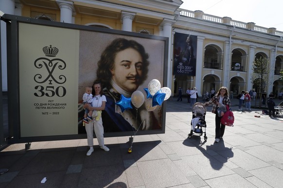 epa10004127 A woman with child poses for a picture in front of a poster depicting Peter the Great at the Nevsky Prospect avenue in St. Petersburg, Russia, 09 June 2022. Peter the Great (1672-1725), he ...