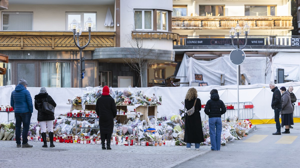 epa12628948 Flowers and candles are pictured in tribute to the victims after the fire at the 'Le Constellation' bar and lounge in Crans-Montana, Switzerland, 05 January 2026. At least 40 peo ...
