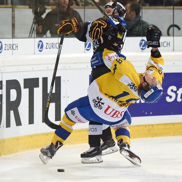 Davos Gregory Sciarono, left, goes out after a check against Luganos Alessio Bertaggia, right, during the game between Switzerlands HC Lugano and Switzerlands HC Davos at the 90th Spengler Cup ice hoc ...