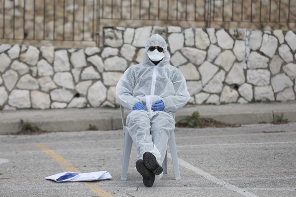 epa08264501 An Israeli security guard wearing a protective suit sits near a special sterile voting station for people in quarantine on coronavirus suspicion during the Israeli legislative election, in ...