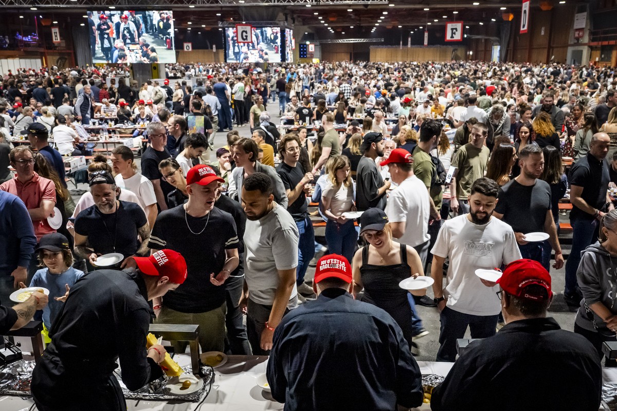 epa12012071 Participants line up to receive plates with raclette cheese during the attempt to beat the record for the world's largest raclette in Martigny, Canton of Valais, Switzerland, 05 April ...
