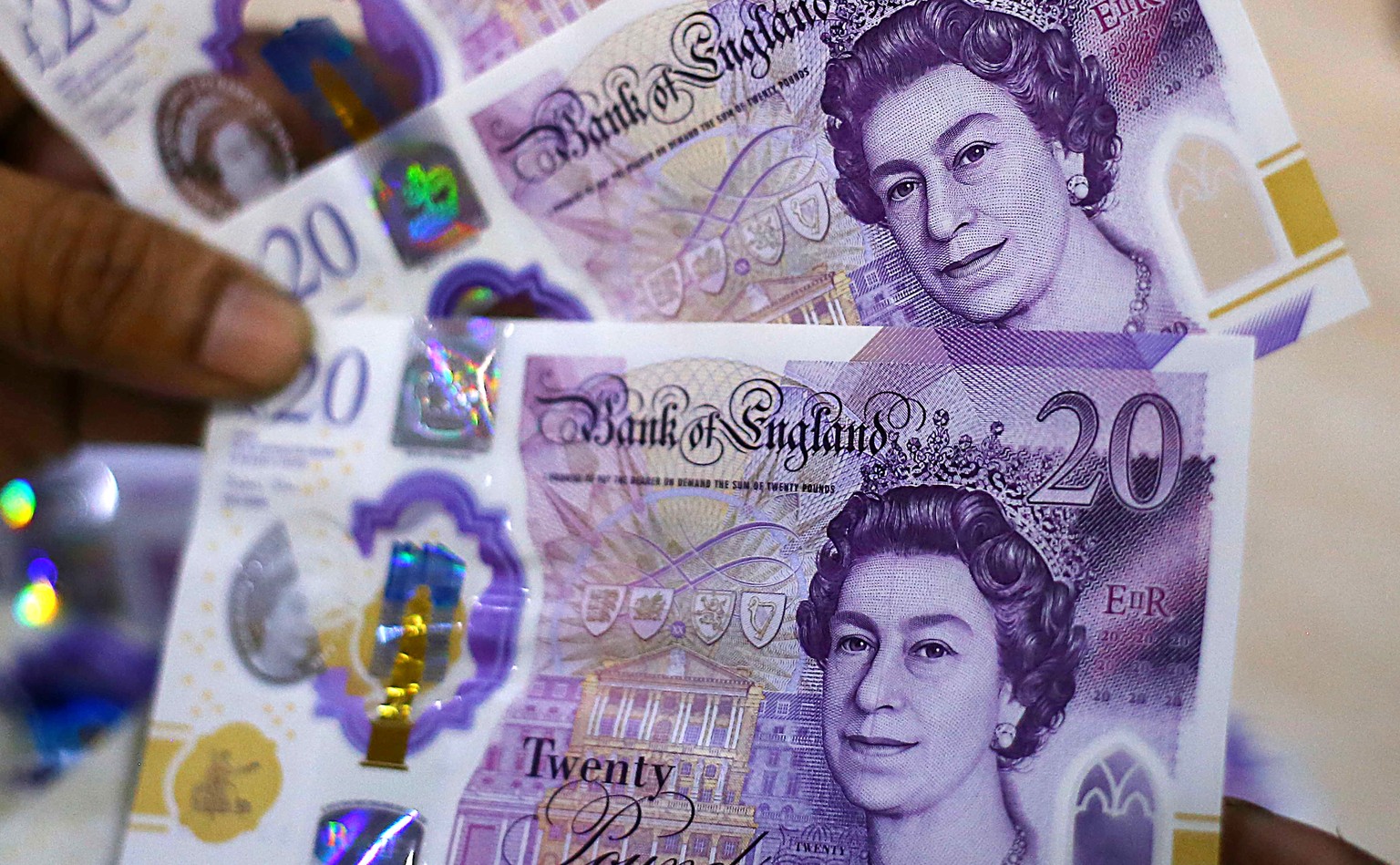 epa10201228 A worker holds Pound sterling banknotes at a money exchange company in Karachi, Pakistan, 23 September 2022. The British pound fell more than 2 percent against the Dollar on 23 September a ...