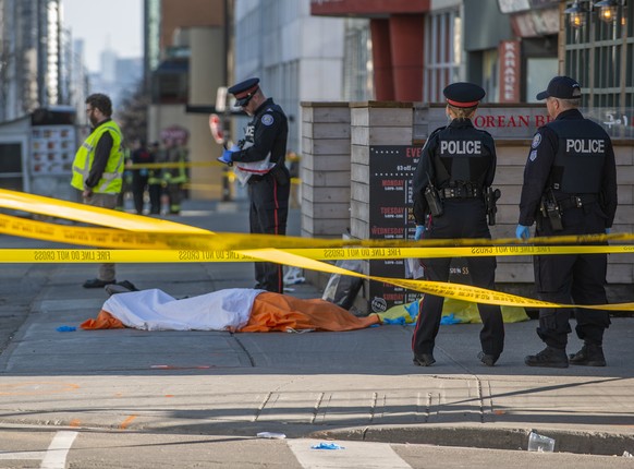 epaselect epa06688068 Toronto police officers stand by a covered body on Yonge Street in northern Toronto, Canada, 23 April 2018. Nine people were killed and 16 injured when a man driving a white van  ...