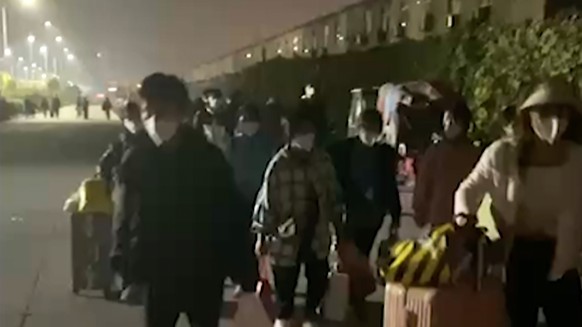 In this photo taken from video footage and released by Hangpai Xingyang, people with suitcases and bags are seen leaving from a Foxconn compound in Zhengzhou in central China&#039;s Henan Province on  ...