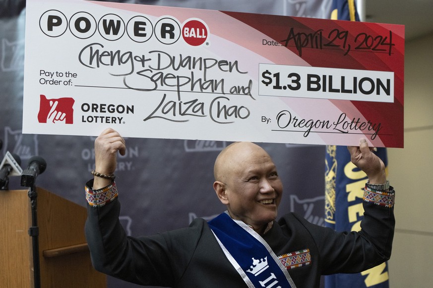 Cheng &quot;Charlie&quot; Saephan holds display check above his head after speaking during a news conference where it was revealed that he was one of the winners of the $1.3 billion Powerball jackpot  ...