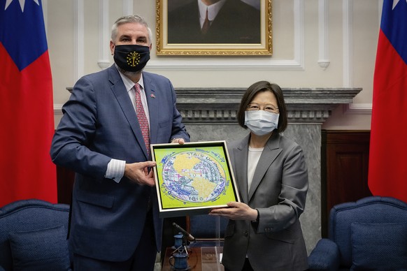 In this photo released by the Taiwan Presidential Office, Taiwan&#039;s President Tsai Ing-wen at right exchanges gifts with U.S. Indiana Governor Eric Holcomb during a meeting at the Presidential off ...
