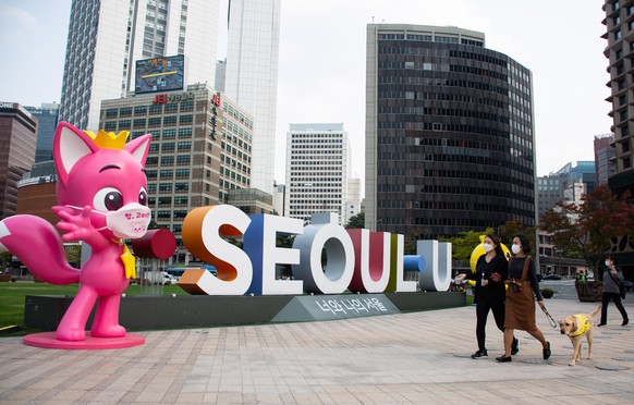 epaselect epa08736975 People wearing a masks walk outside Seoul City Hall in Seoul, South Korea, 12 October 2020. The South Korean government decided to lower its social distancing guidelines to the l ...