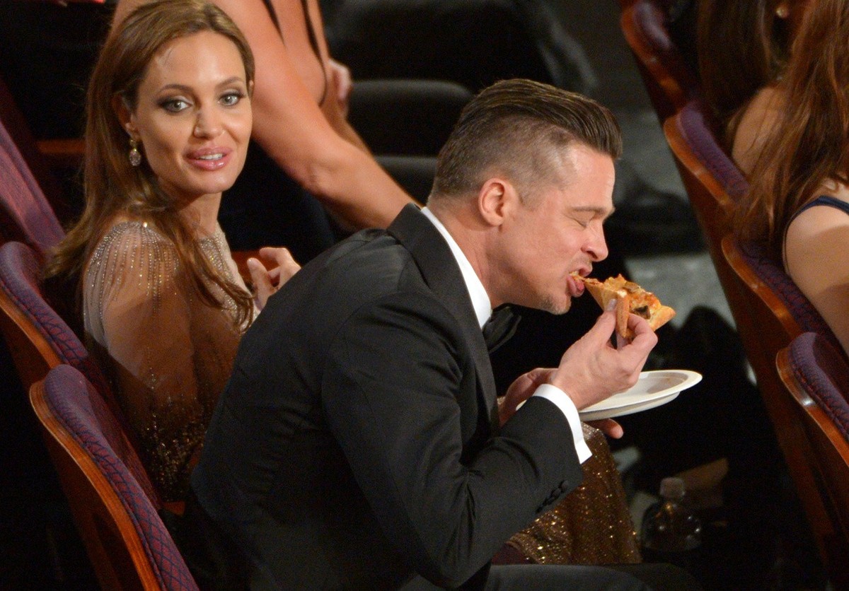Brad Pitt mange une pizza lors des Oscars le 2 mars 2014, à Los Angeles. (Photo by John Shearer/Invision/AP)