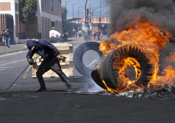A man burns tires during a march against the government of Guillermo Lasso called mainly by Indigenous organizations, in Quito, Ecuador, Thursday, June 16, 2022.(AP Photo/Dolores Ochoa)