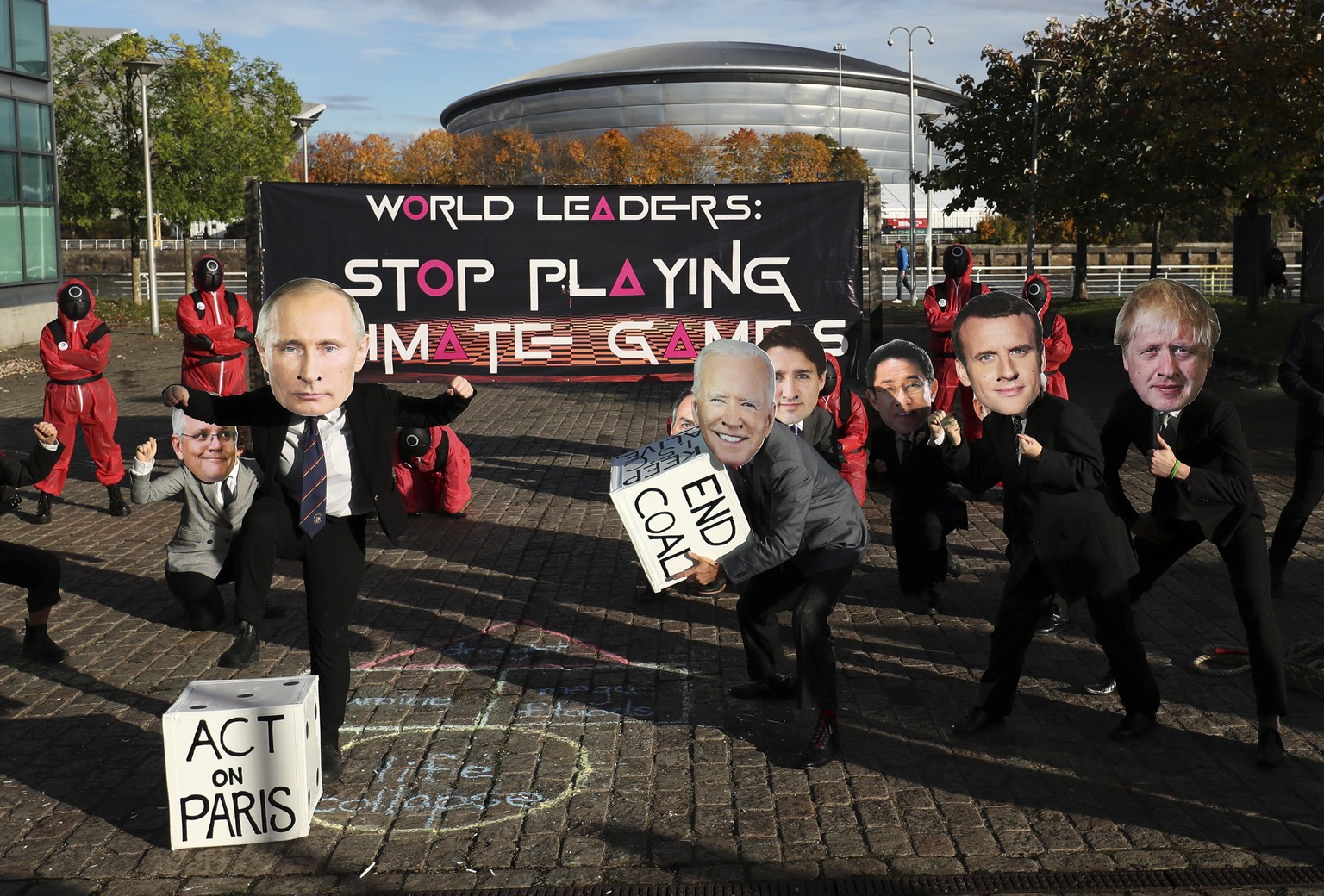 Climate campaigners wearing masks of world leaders enact a &quot;Squid Game&quot; themed protest stunt with a campaigner wearing a mask of Russian President Vladimir Putin, front left, and another wea ...