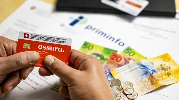 Une illustration pour la hausse des primes d&#039;assurance-maladie, montre une carte suisse d&#039;assurance-maladie LAMal (KVG) de l&#039;assurance Assura, devant des billets de banque suite a l&#03 ...