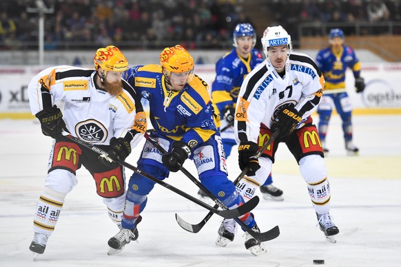 Linus Klasen, links, und Philippe Furrer von Lugano, gegen Perttu Lindgren von Davos, Mitte, beim Eishockey-Qualifikationsspiel der National League A zwischen dem HC Davos und dem HC Lugano, am Freita ...