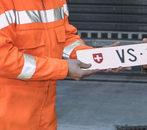 Otto Ruppen, links, nimmt das Autokennzeichen VS 1 von Staatsrat Oskar Freysinger (SVP-VS), rechts, in Empfang und platziert das Nummernschild auf einem Mahnmal vor seiner Ruppen Bau und Transport AG  ...