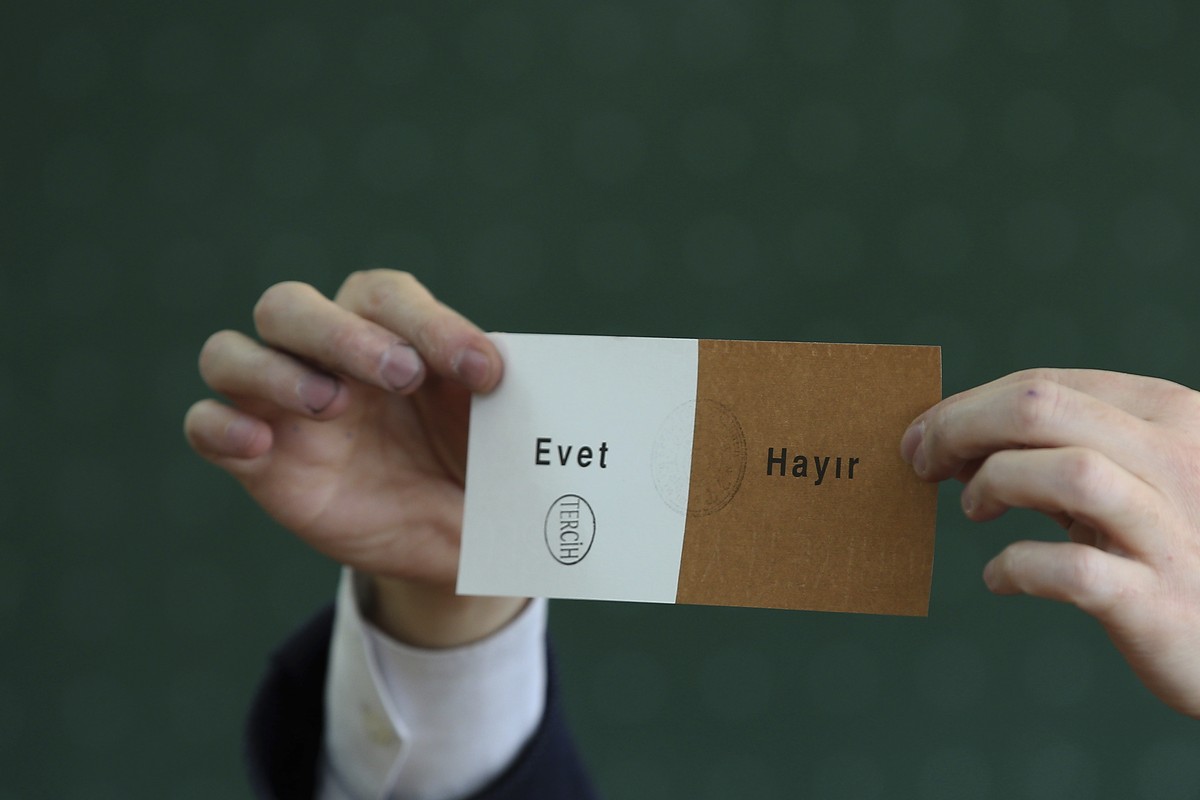 A member of an electoral committee holds a ballot stamped in favor of "Yes" inside a polling station in Istanbul, on Sunday, April 16, 2017. With 97 percent of the ballots counted in Turkey& ...