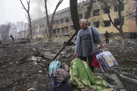 FILE - A woman walks outside a maternity hospital that was damaged by shelling in Mariupol, Ukraine, Wednesday, March 9, 2022. (AP Photo/Evgeniy Maloletka, File)