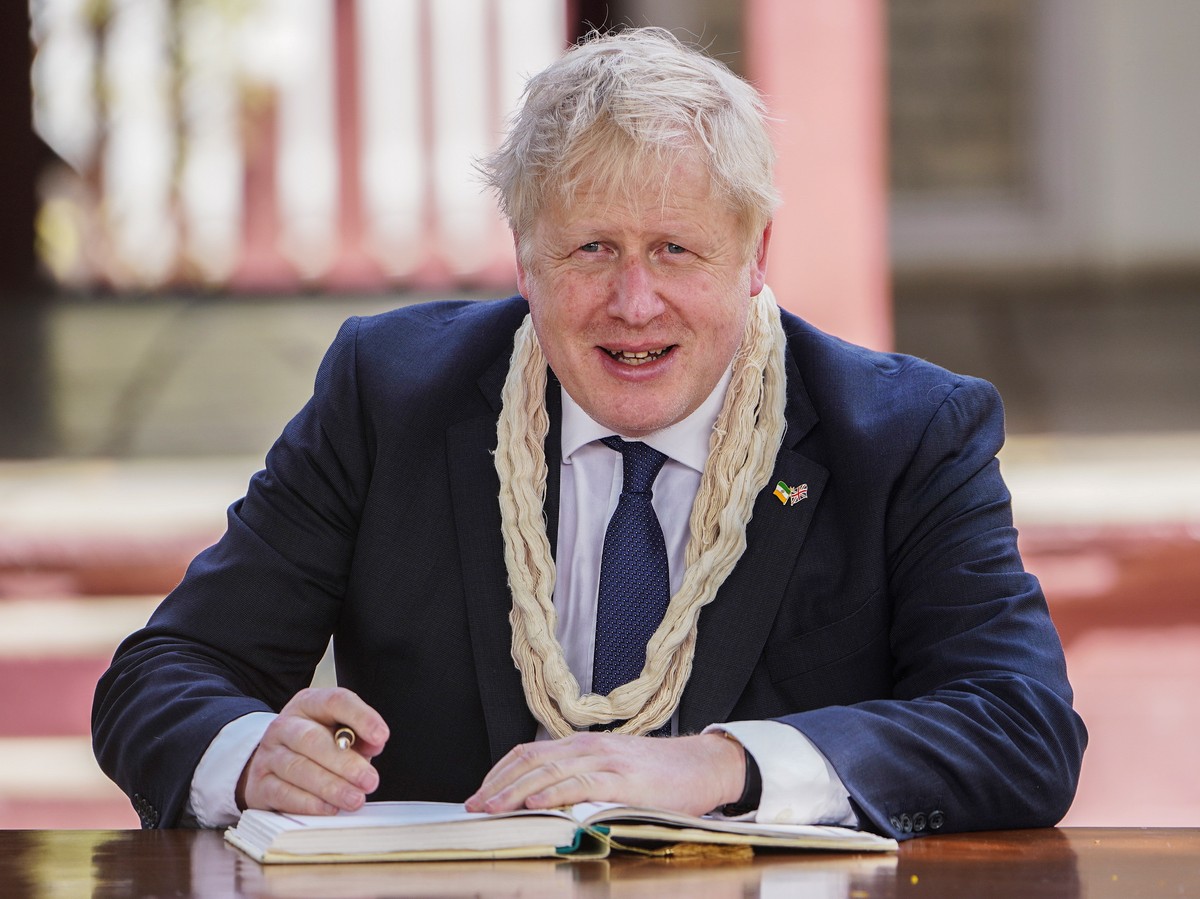 epa09900152 Britain's Prime Minister Boris Johnson writes a remark in a guest book during his visit to the Sabarmati Ashram in Ahmedabad, India, 21 April 2022. Boris Johnson is in Ahmedabad durin ...