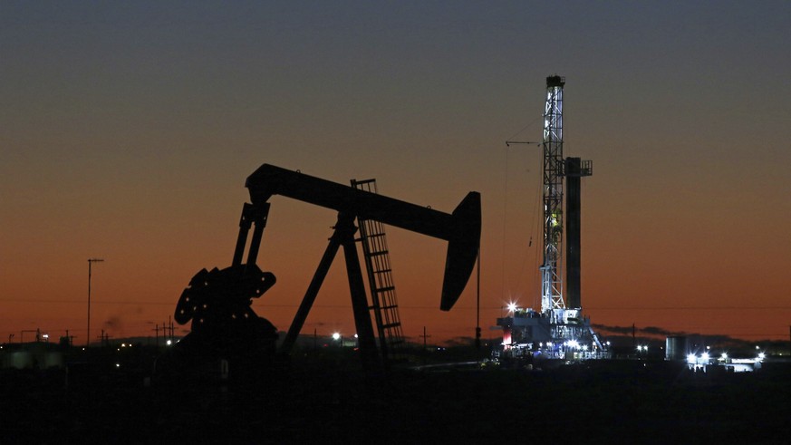 In this Tuesday, Oct. 9, 2018, photo, an oil rig and pump jack are at work as seen from the roadside of FM 1788 in Midland, Texas. (Jacob Ford/Odessa American via AP)